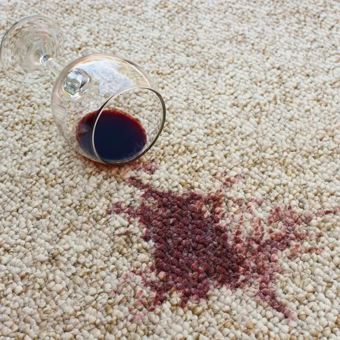 Red wine spilled on carpet leaving a dark red stain.